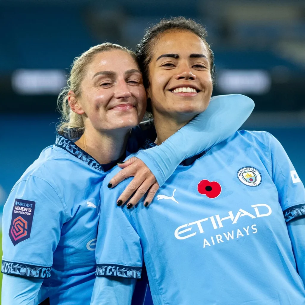 Two Manchester City players smiling and hugging