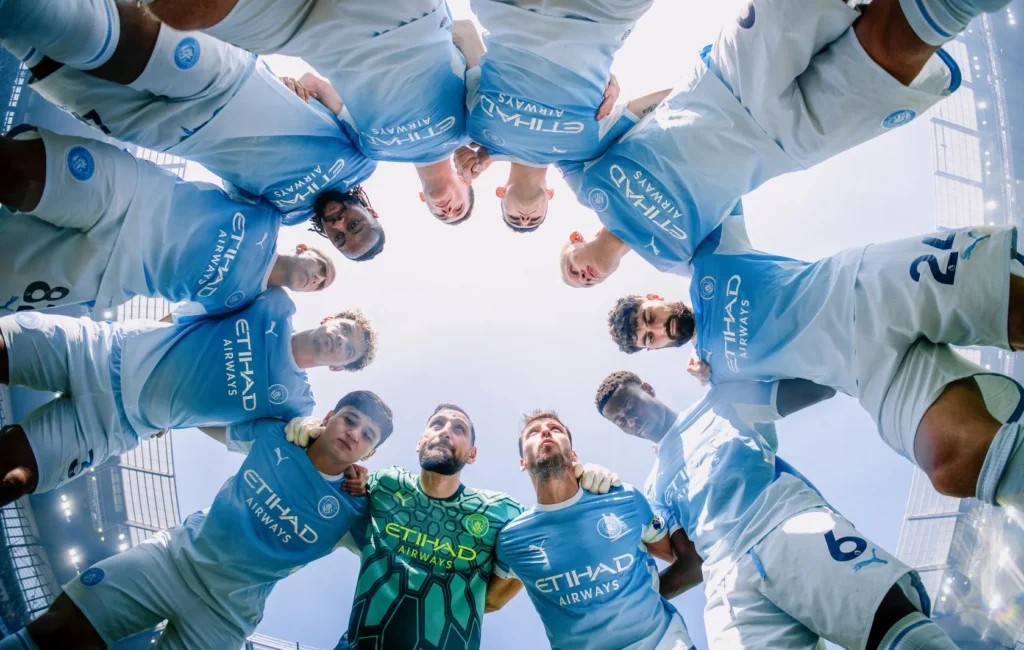 Manchester City players in a huddle, seen from below